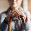 old woman, her hands resting on a cane