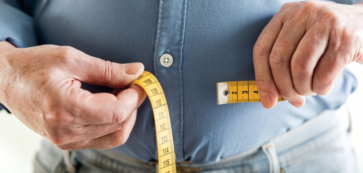 man's hands holding tape measure aound belly