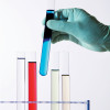 gloved hand holding test tubes with color liquid
