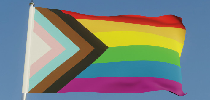 Inclusive LGBTQI+ Pride Flag Fluttering against a blue sky