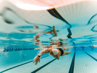 Underwater photo of an adult man with an amputated arm swimming in an indoor pool