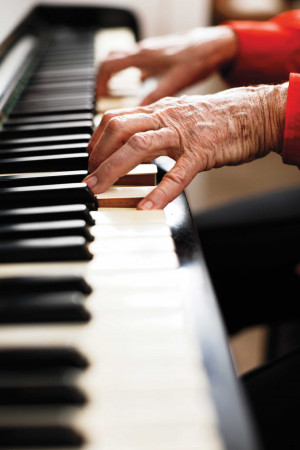 Looking across keyboard to wrinkled hands playing piano